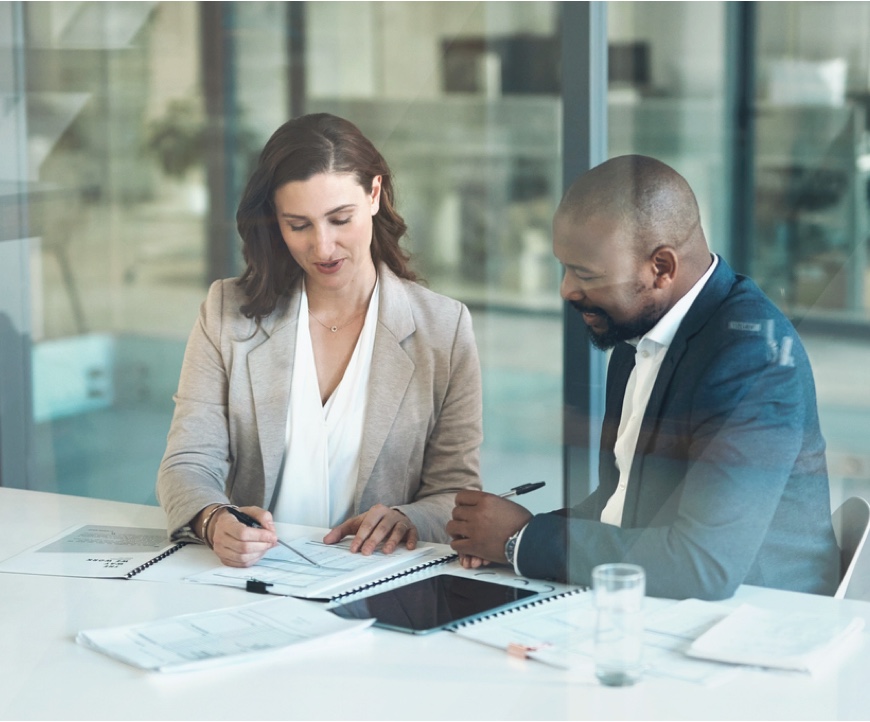 Two business professionals reviewing documents at a conference table.