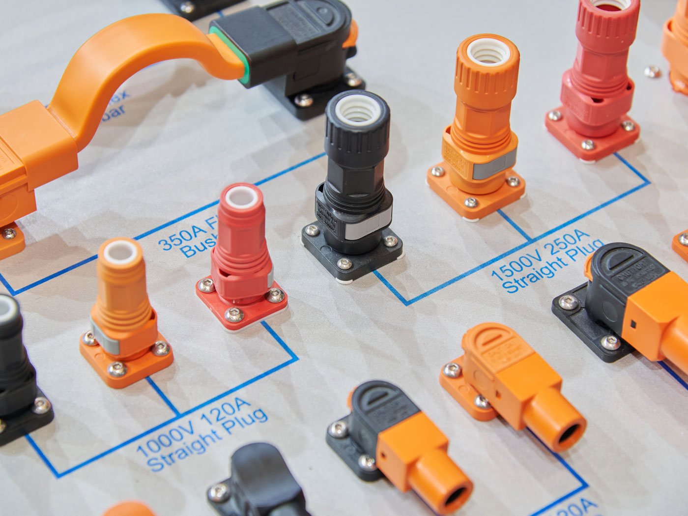 Assorted high‑voltage electrical connectors and plugs on a display board, labeled 350A, 1000V, 1500V, 250A, 120A.