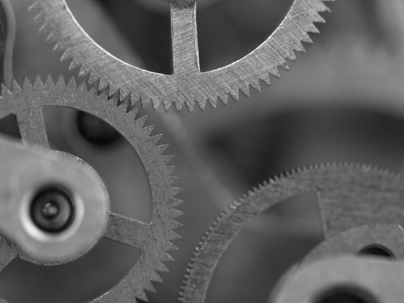 Close-up black and white photo of interlocking metal gears with detailed teeth, showing mechanical precision.